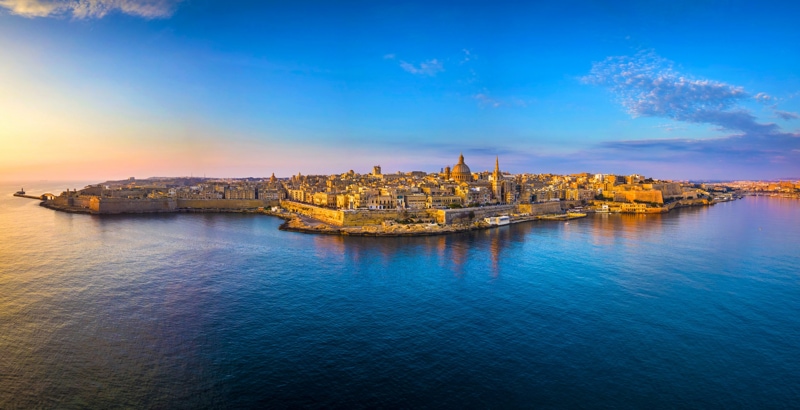 Valletta, Malta, bathed in warm sunset hues, showcasing its historic architecture and beautiful skyline.
